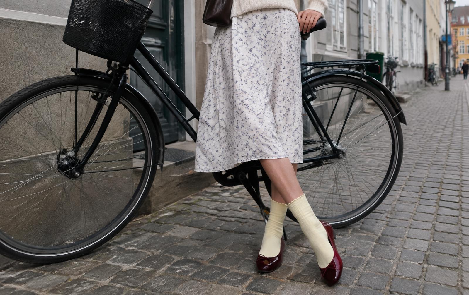 Butter yellow scalloped socks with burgundy ballet flats beside a bicycle on a cobbled Copenhagen street